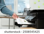 Woman using modern printer at workplace indoors, closeup
