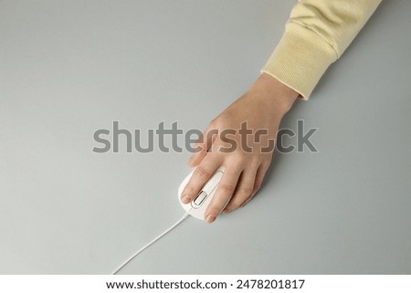 Woman using modern wired computer mouse on grey background, top view. Space for text