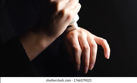 Woman Using Moisturizing Cream To Prevent Dry Skin Of Her Hands. Concept. Close Up Of Tender Female Hands Applying Some White Lotion On Her Hands Isolated On Black Background.