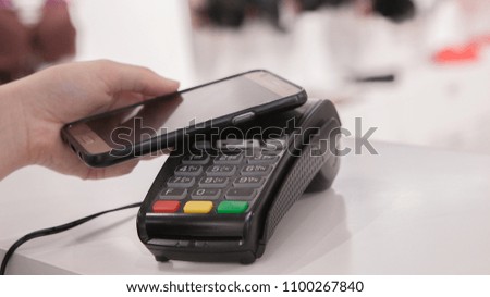 Woman using NFC technology for payment in the shop.