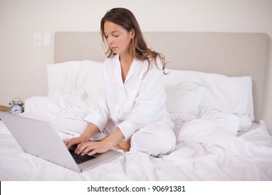 Woman using a notebook in her bedroom. Working from home in quarantine lockdown. Social distancing Self Isolation - Shutterstock ID 90691381