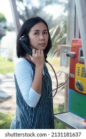 Woman Using Old Style Public Pay Phone In Telephone Booth.