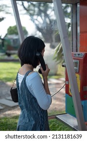 Woman Using Old Style Public Pay Phone In Telephone Booth.