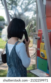 Woman Using Old Style Public Pay Phone In Telephone Booth.