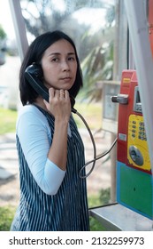 Woman Using Old Style Public Pay Phone In Telephone Booth.