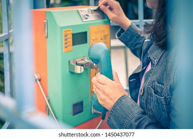 Woman Using Old And Weathered Oldstyle Plublic Pay Phone In Phone Booth.