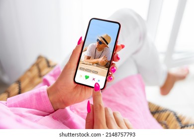 Woman using online dating app on phone and viewing someone's profile - Shutterstock ID 2148757793