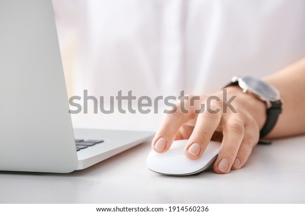 Woman using PC mouse while working on computer at\
table, closeup
