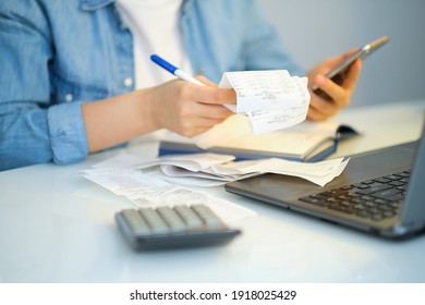 woman using a pen writing on bank account book while holding the bills to calculate in living room at home. Expenses, account, taxes, home budget concept - Shutterstock ID 1918025429