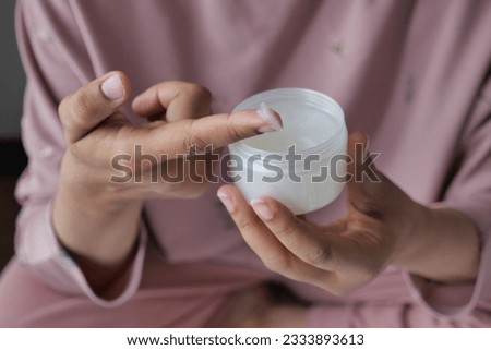 woman using petroleum jelly onto skin at home close up.