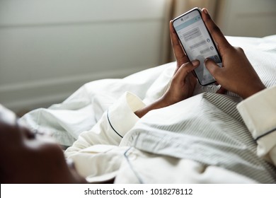 A Woman Using A Phone In Bed