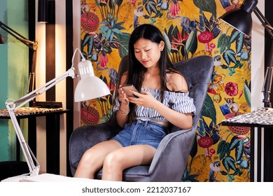 Woman Using Phone Sitting On A Beauty Salon Chair