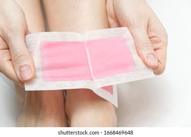 Woman Using Pink Wax Strips. Beautiful Woman Doing Depilation For Her Legs With Waxing, Isolated On White