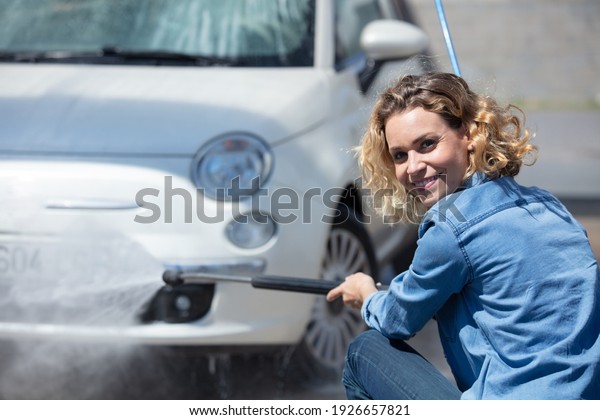 woman using power\
washer to clean her car