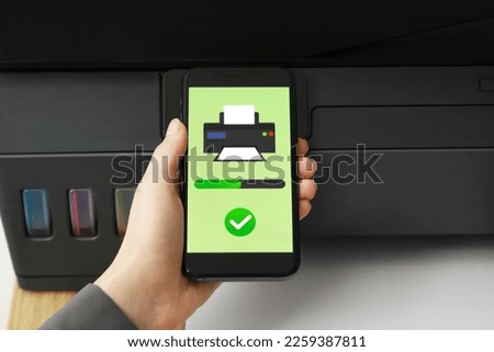 Woman using printer management application on smartphone at table, closeup. Image on device screen.