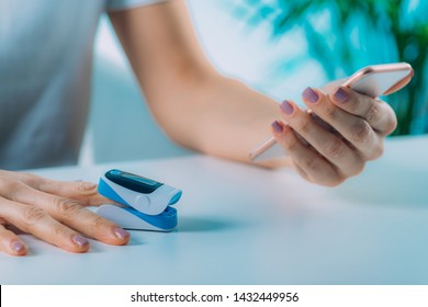 Woman Using Pulse Oximeter And Smart Phone, Measuring Oxygen Saturation 