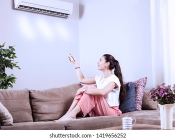 Woman Using Remote Control Of Airconditioner