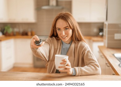 Woman Using Remote Control While Sitting In Kitchen - Powered by Shutterstock