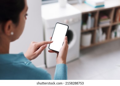 Woman using smart appliances at home, she is connecting the washing machine to her phone, blank display on the smartphone - Powered by Shutterstock