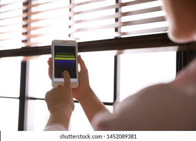 Woman Using Smart Home Application On Phone To Control Window Blinds Indoors, Closeup