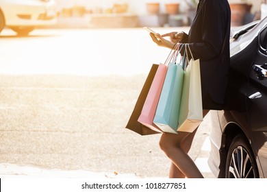 Woman Are Using Smart Phone After Shopping In The Mall  And Standing In Car Park