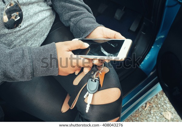 Woman using\
smart phone and key car with\
sunglasses