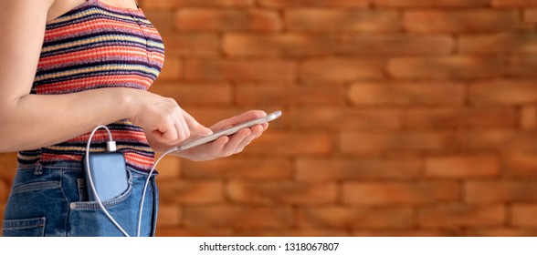 Woman Using Smart Phone While Charging On The Power Bank.