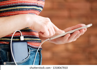 Woman Using Smart Phone While Charging On The Power Bank.