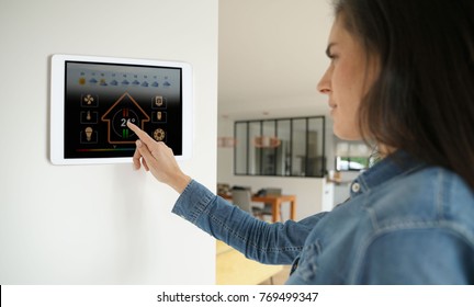 Woman using smart wall home control system 