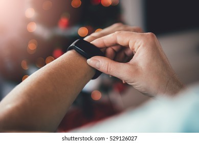 Woman using smart watch with a christmas tree in the background