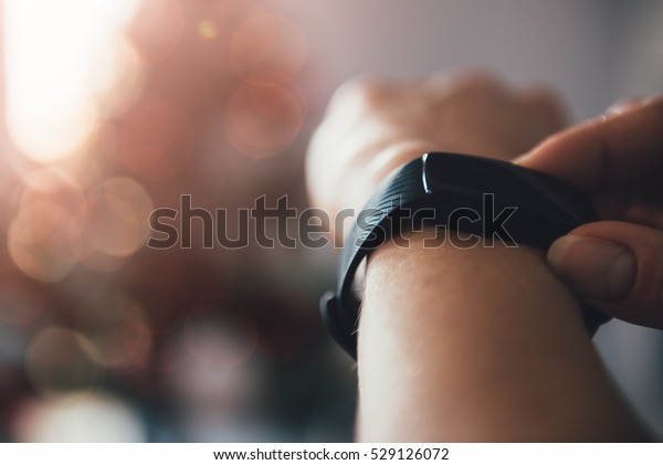 Woman using smart watch with a christmas tree\
in the background