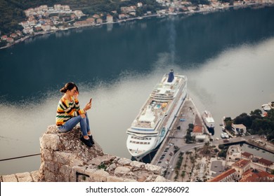 Woman Using Smartphone App And Travel With Cruise Ship View. Aerial View On Cruise Liner. Kotor, Montenegro.