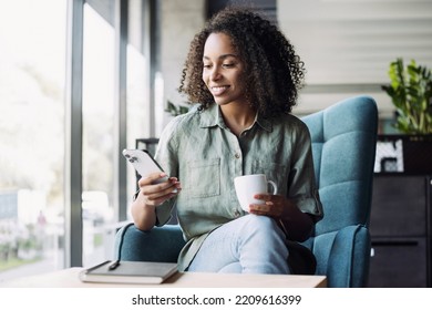 Woman using smartphone at cafe. African american businesswoman looking at mobile phone, has coffee break - Powered by Shutterstock