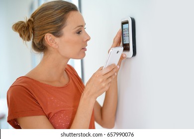 Woman using smartphone to control home connectivity interface - Powered by Shutterstock