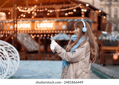 Woman Using Smartphone at Festive Winter Market With String Lights - Powered by Shutterstock