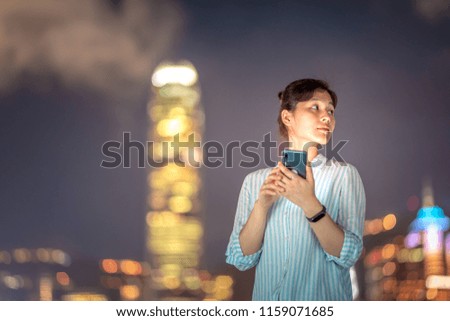 Woman using smartphone in front of Victoria Harbor, Hong Kong