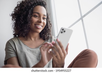 Woman using smartphone at home. Mixed race girl looking at mobile phone. Communication, leisure, connection, mobile apps, technology, lockdown, web chat, lifestyle concept
