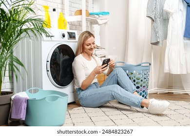 Woman Using Smartphone Near White Laundry Machine in Home Laundry Room - Powered by Shutterstock