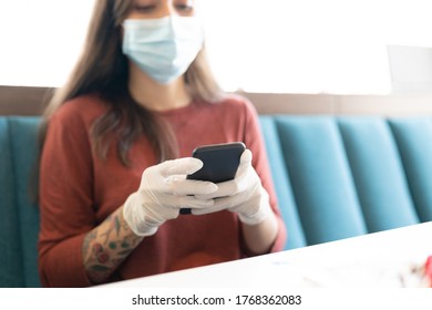 Woman using smartphone in restaurant during coronavirus crisis - Shutterstock ID 1768362083