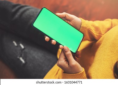 Woman using smartphone watching green screen on mobile phone, online enjoying reading social media at home close up hands - Powered by Shutterstock