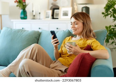 Woman using smartphone while drinking coffee at her home in the morning - Powered by Shutterstock