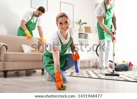 Woman using sponge and detergent for floor cleaning with her team in living room