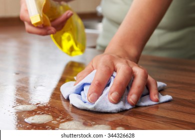 Woman Using Spray Cleaner On Wooden Surface