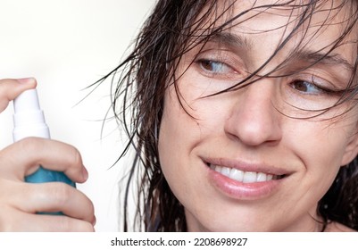 Woman Using Spray On Wet Hair Isolated.smiling Girl With Wet Hair Long Bangs Chaotic On Face Hold In Hand Bottle With Oil Spray Keratin For Extra Shine Healthy Structure.parts Of Face Closed Eye Relax