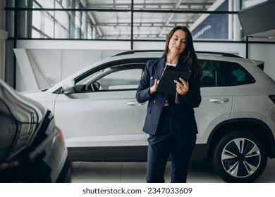 Woman using tablet and choosing a car in car showroom - Powered by Shutterstock