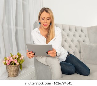 Woman using tablet computer while sitting in sofa at home