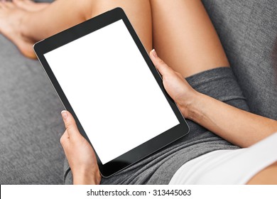Woman using tablet computer while sitting on a cosy sofa. View from above. Clipping path included.