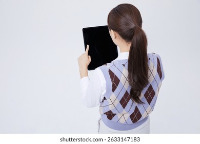 Woman using tablet device while standing indoors at home, exploring digital content with focused expression