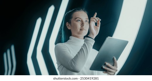 Woman using tablet in futuristic setting with glowing lights. Woman portrait with technology, focused on digital interaction, surrounded by modern design elements. Modern futuristic technology. - Powered by Shutterstock