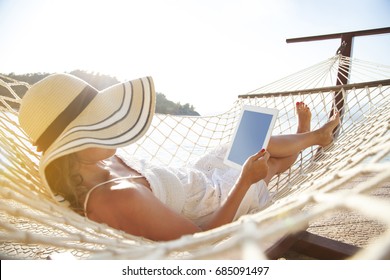 Woman using tablet pc on hammock - Powered by Shutterstock